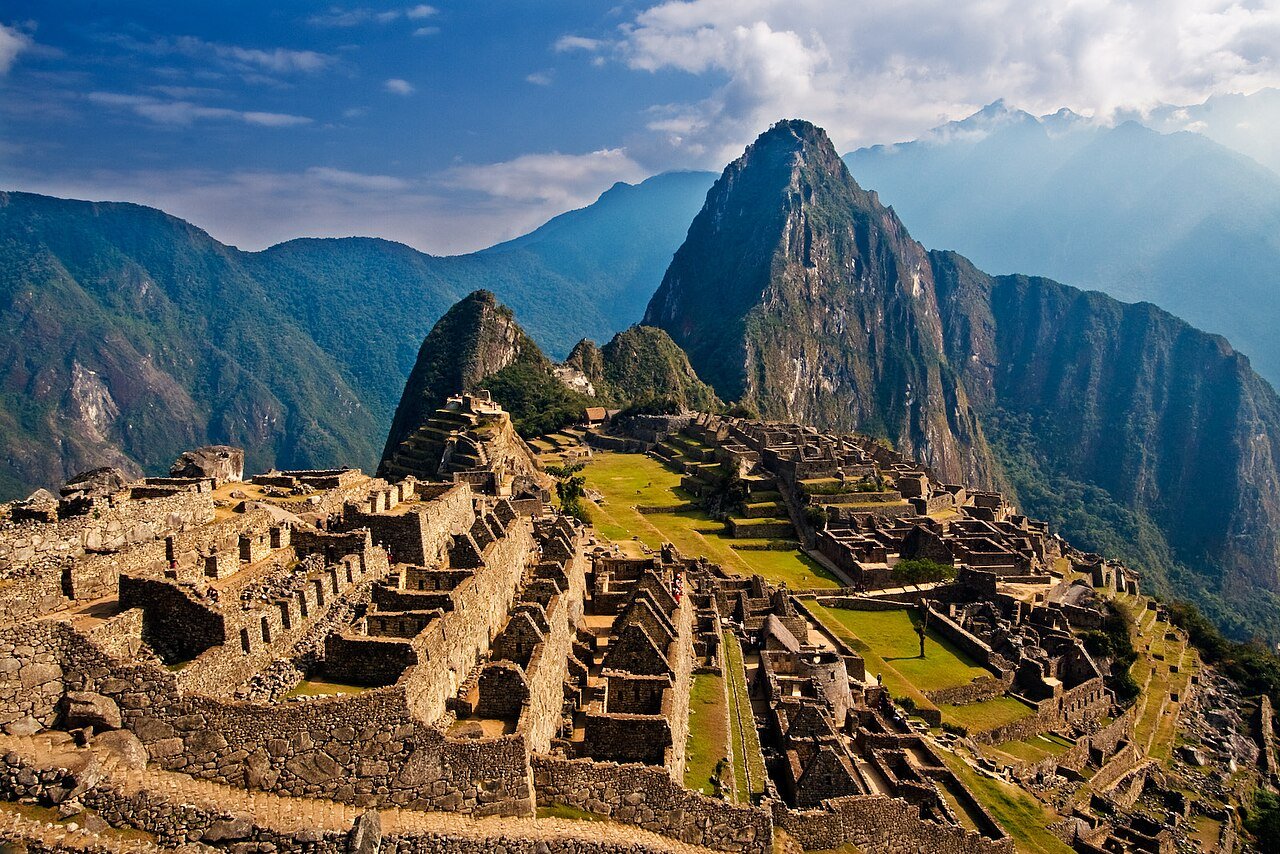 Visitantes en terrazas de Machu Picchu con montañas verdes al fondo