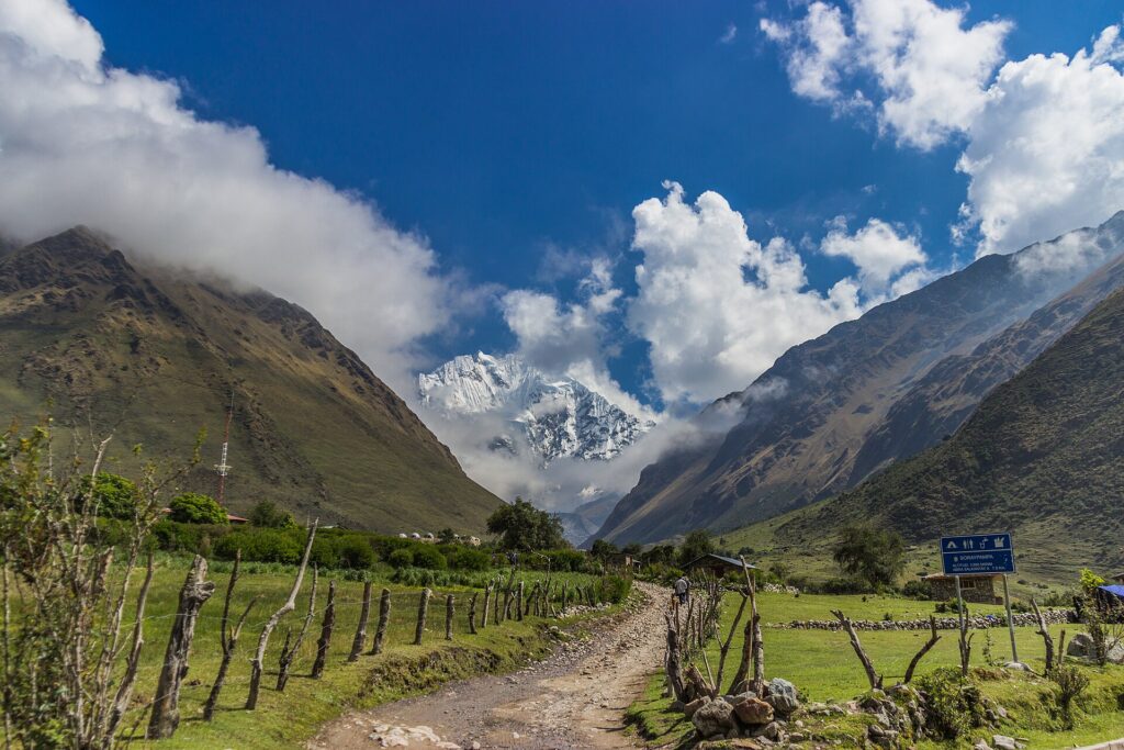 Sendero del Salkantay Trek hacia pico nevado andino bajo cielo azul
