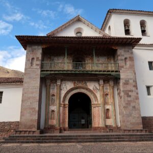 Andahuaylillas: fachada del templo de San Pedro Apóstol con muros blancos, portada de piedra con pinturas, balcón de madera y campanario, bajo un cielo azul
