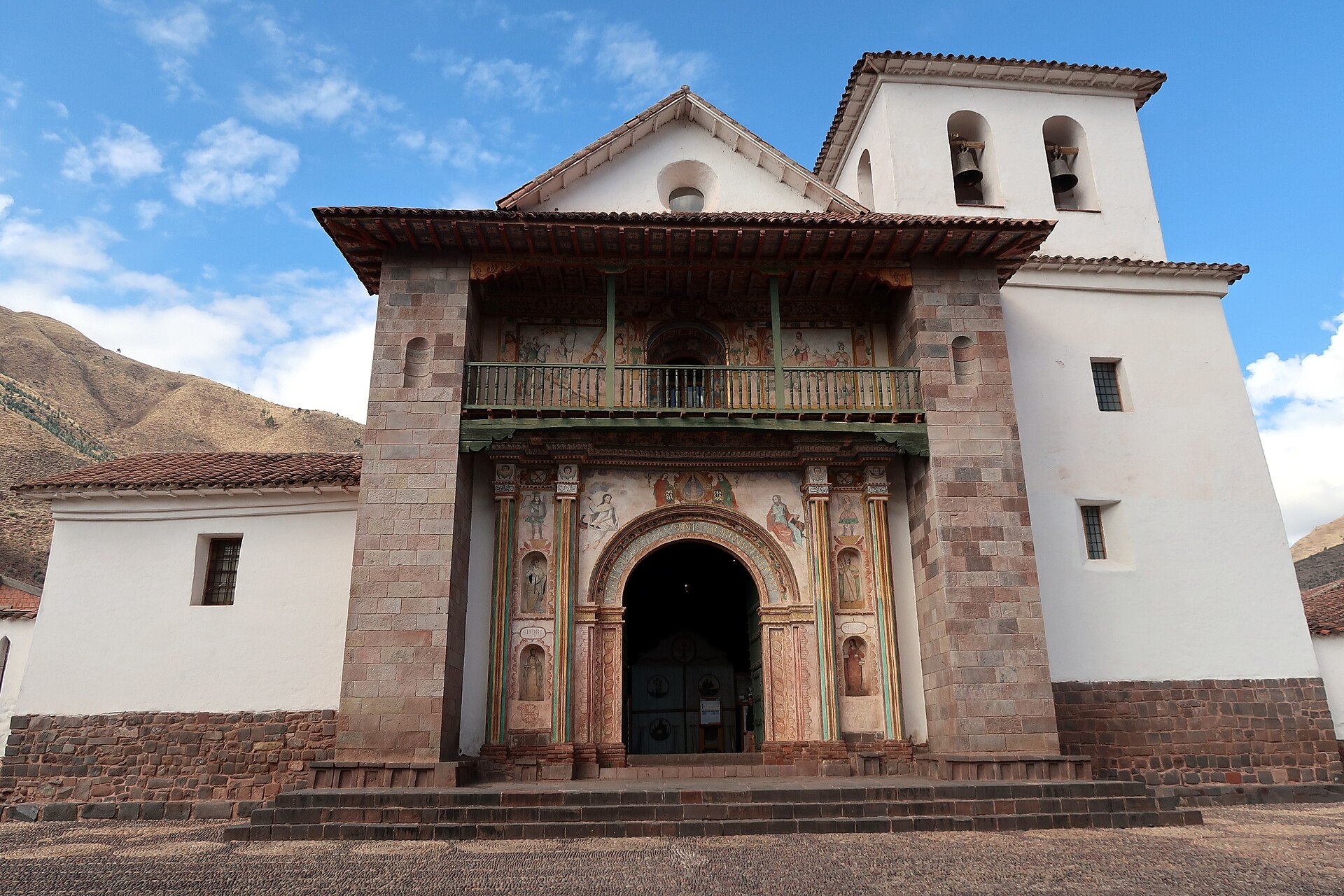 Andahuaylillas: fachada del templo de San Pedro Apóstol con muros blancos, portada de piedra con pinturas, balcón de madera y campanario, bajo un cielo azul