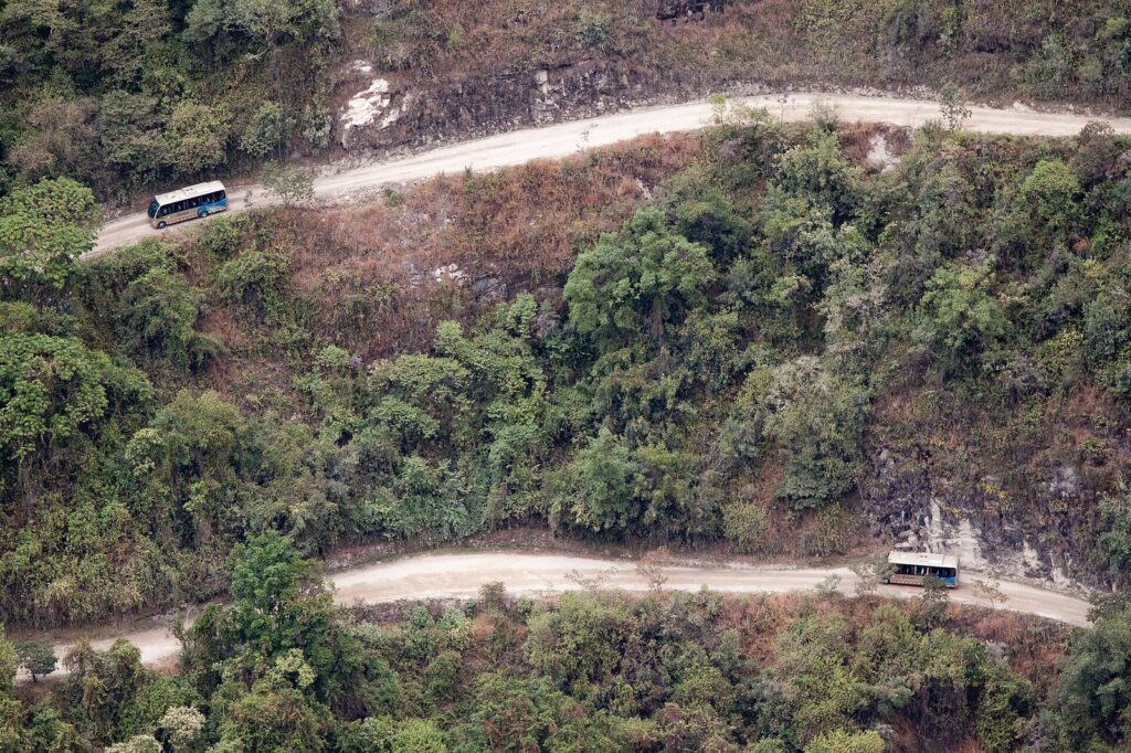 Buses turísticos en la carretera en zigzag que sube desde Aguas Calientes hacia Machu Picchu, entre montañas verdes