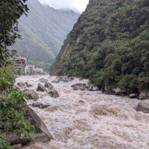 Río Vilcanota, que también pasa junto al museo de sitio de Machu Picchu: aguas turbias entre grandes rocas y laderas de bosque, en Machupicchu Pueblo
