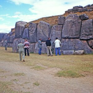 Visitantes junto a los grandes muros de piedra inca de Saqsayhuamán en Cusco bajo cielo azul